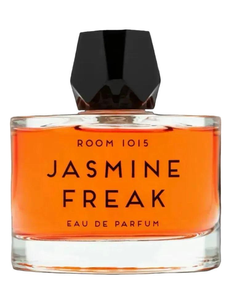 A bottle of Room 1015 Jasmine Freak Eau de Parfum with bright orange liquid and a black faceted cap, set against a solid black background.